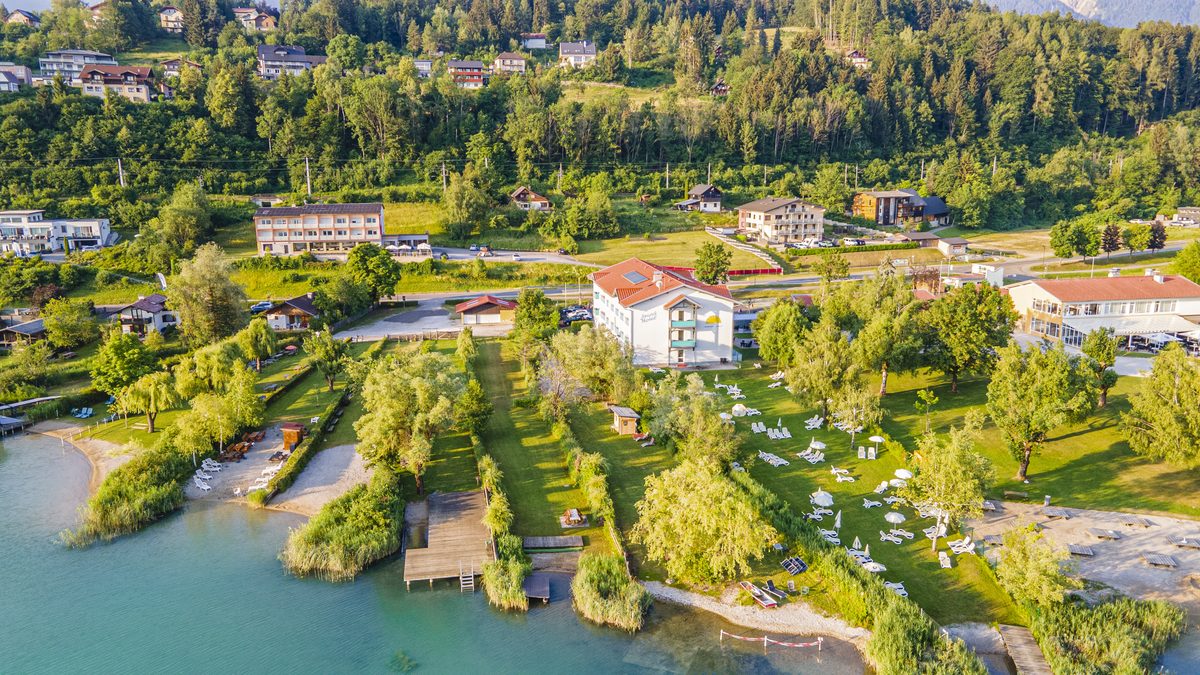 Aerial view of Strandhotel Faak with sunbathing lawn and lake in the evening light