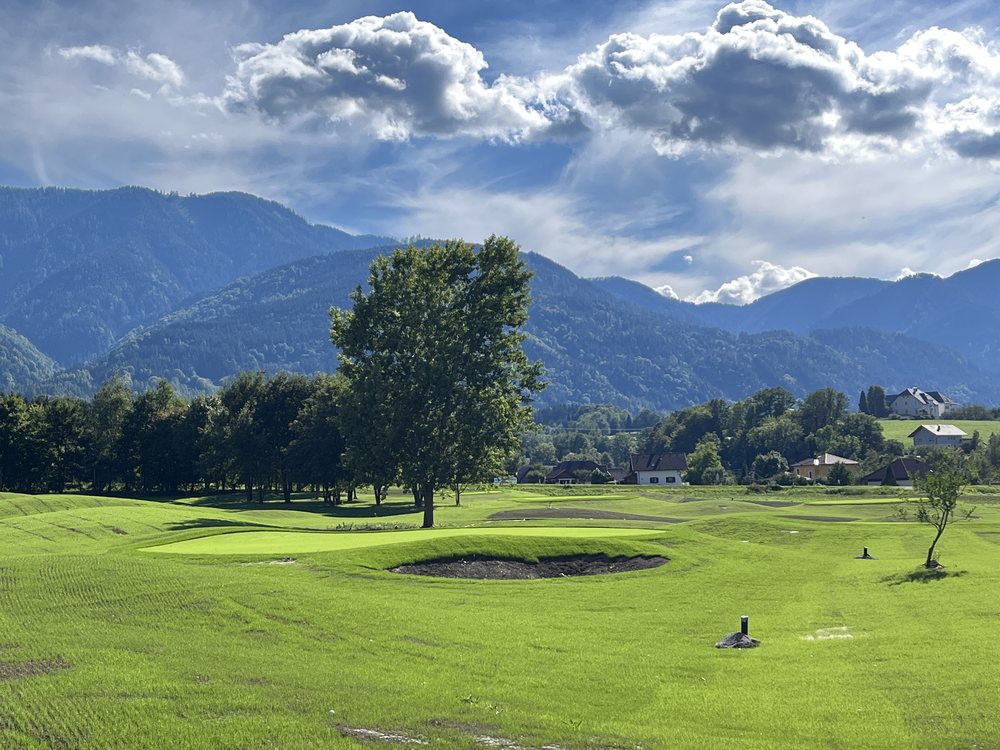 Green with a bunker on the short course of Golfclub Schloss Finkenstein, with the mountains behind