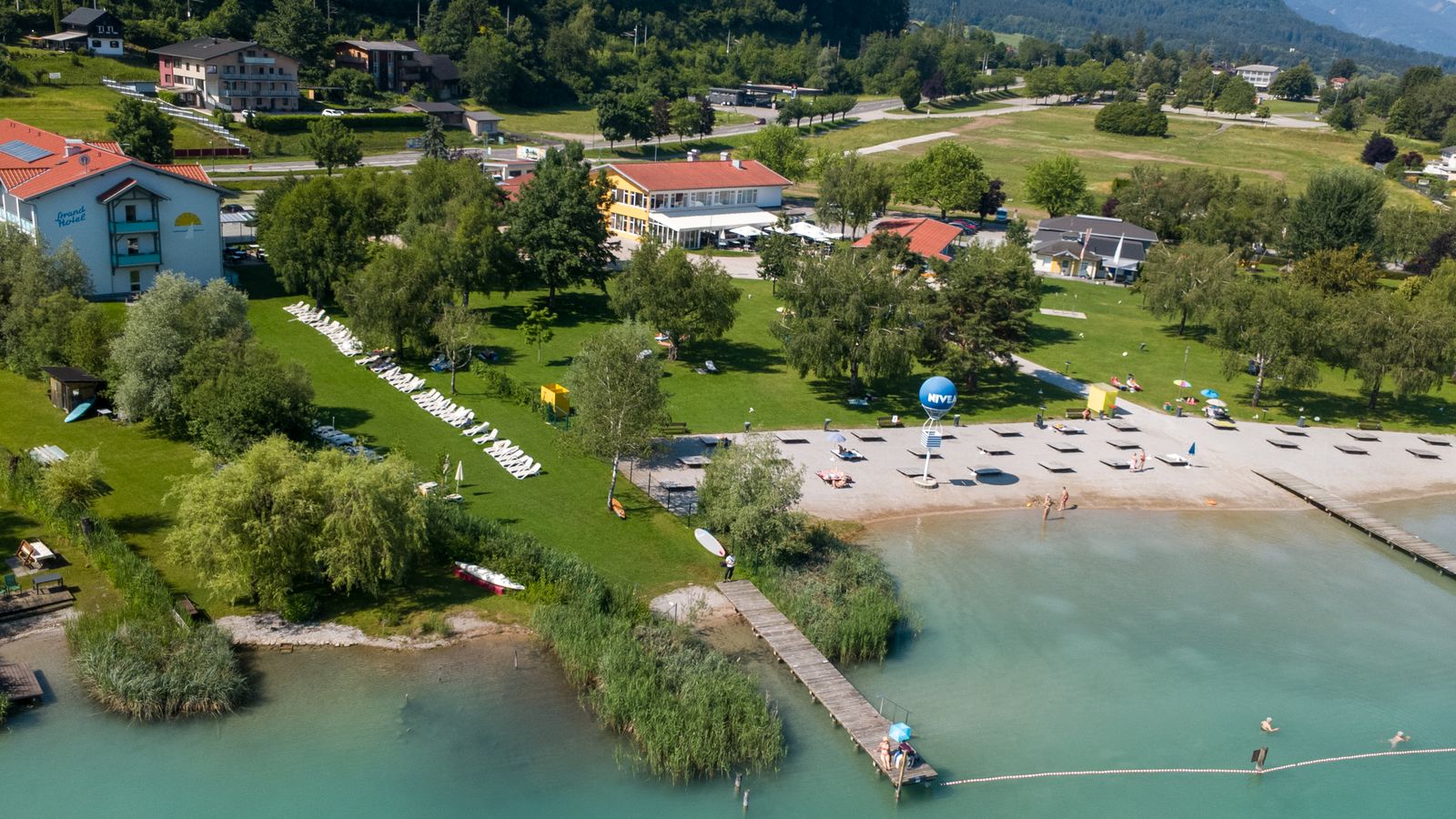 Luftaufnahme: Strandhotel Faak mit Privatstrand und See-Restaurant am Faaker See