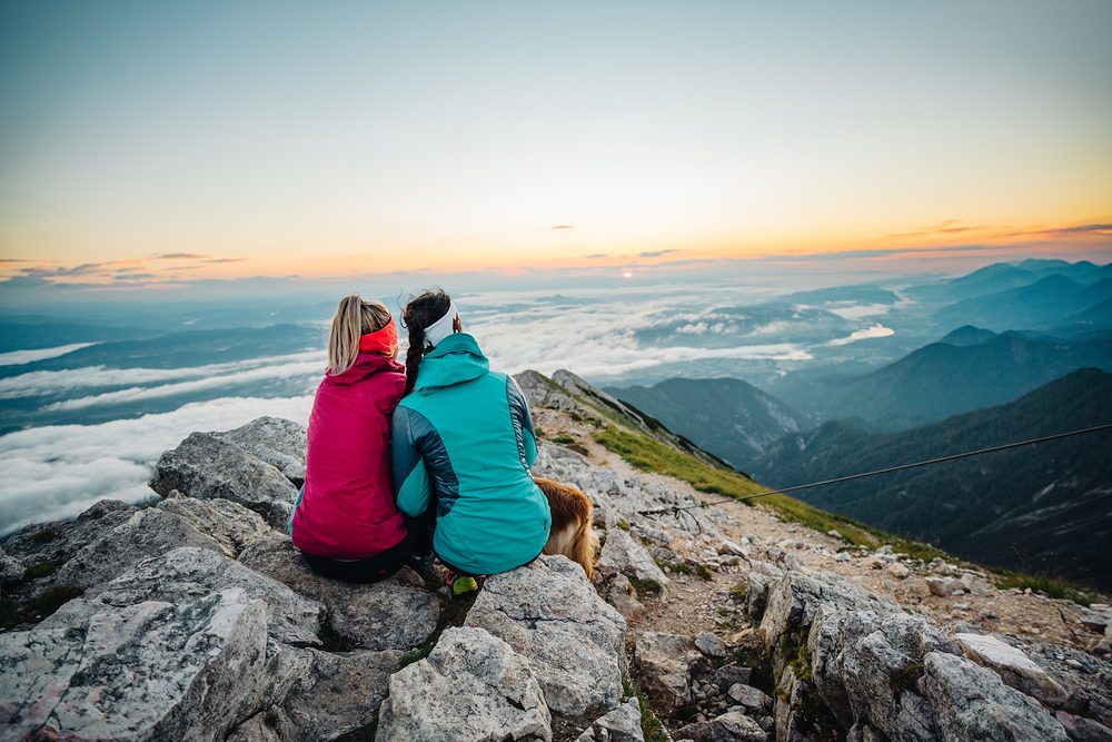 Two hikers at sunrise on the Mittagskogel above a sea of fog