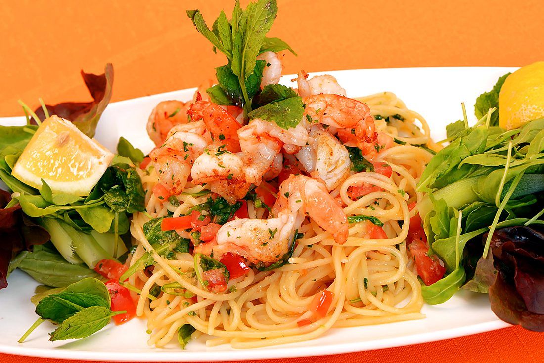 Spaghetti with prawns, fresh herbs and lemon on a plate