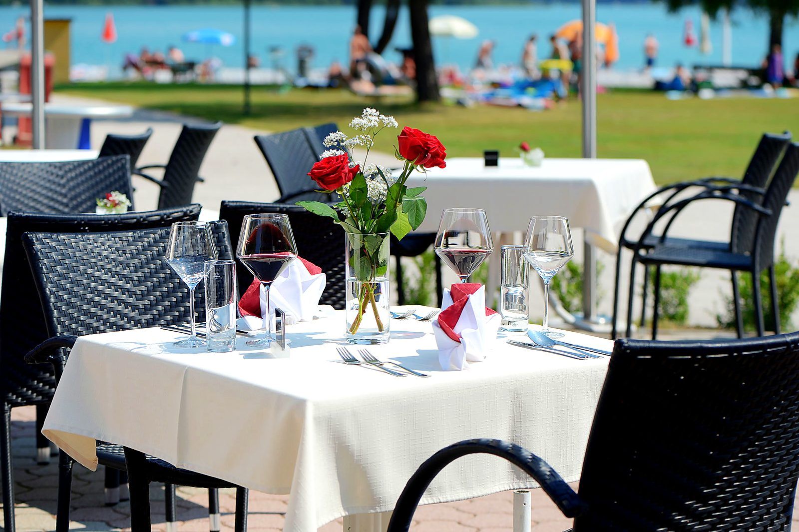 Laid table on the terrace of the lakeside restaurant with a view of Lake Faak