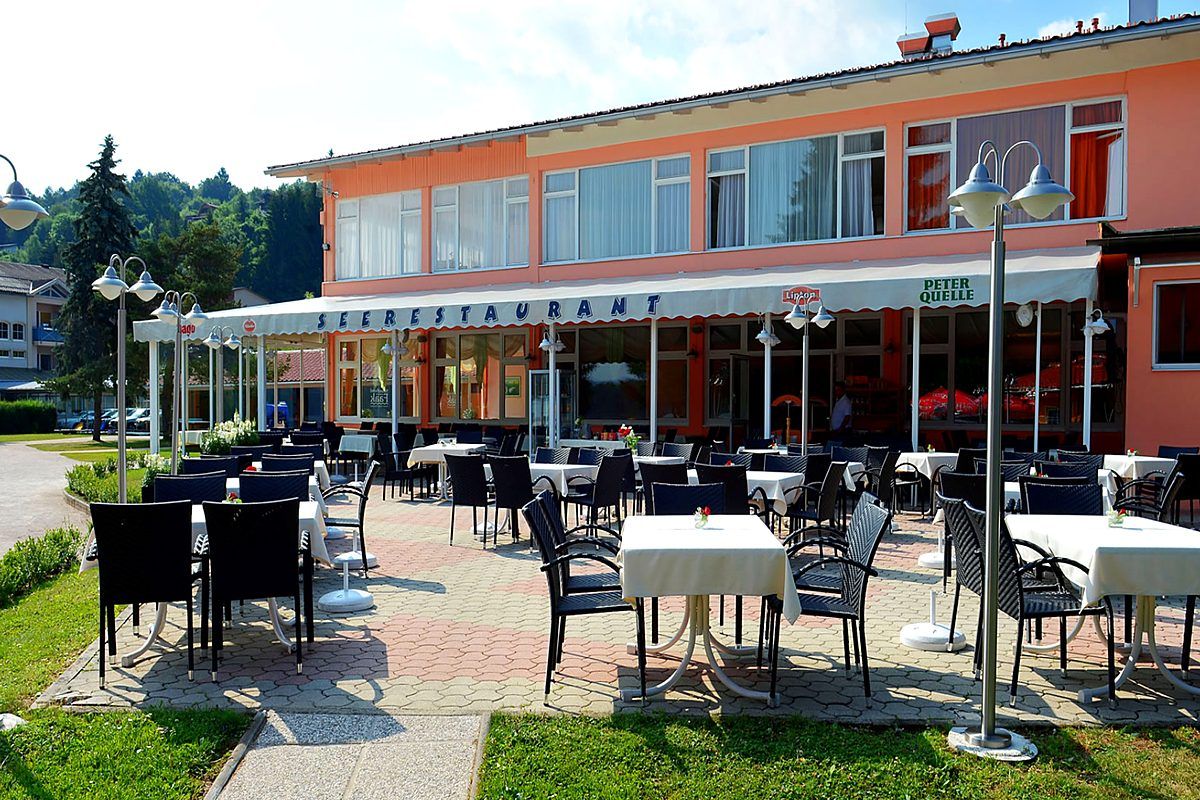 Sunny terrace of the lakeside restaurant with laid tables on Lake Faak