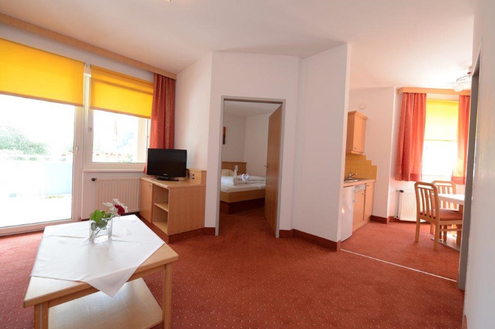 Open-plan living and dining area of Suite Type A with kitchenette and a view into the bedroom
