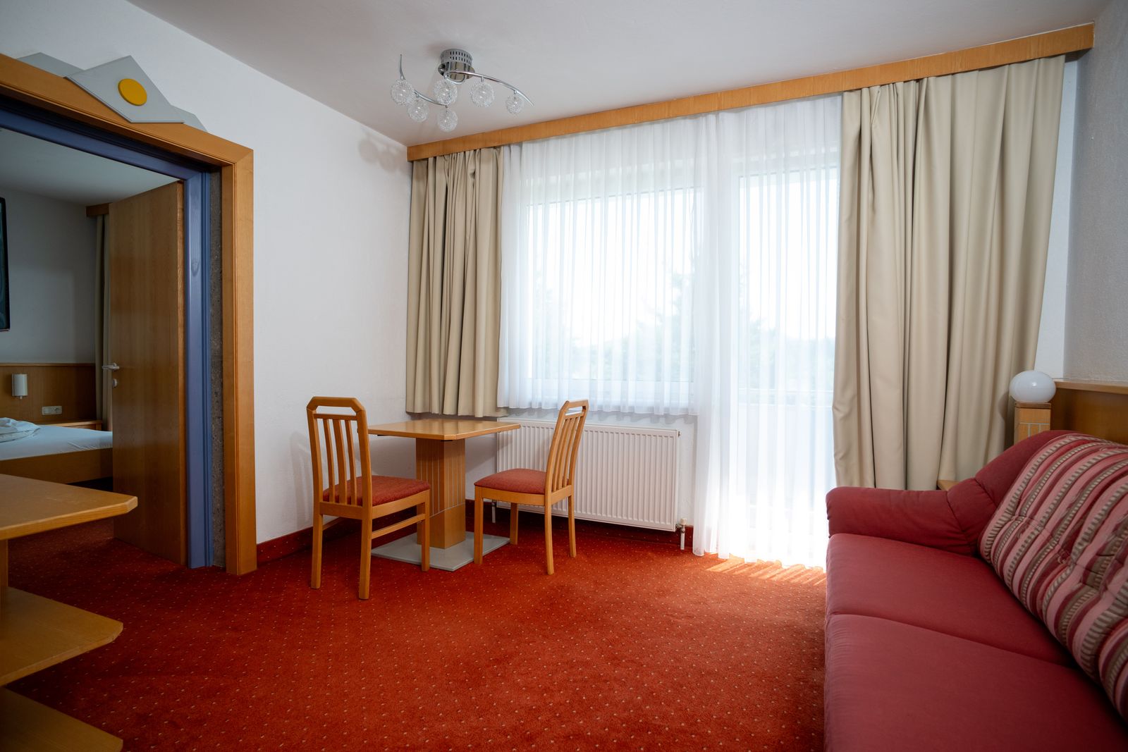 Wohnbereich der Suite Typ A mit gemütlicher Sitzecke und Blick ins Schlafzimmer